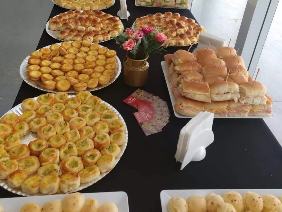 Mesa de coffee break com salgados, sanduíches, quiches e pão de queijo